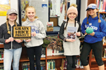 Four middle-grade students hold books and objects related to their read-a-thon to raise money for the Grain of Rice project (Photo: Batesville (Ind.) Intermediate School)