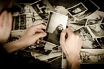 photo of hands holding a black and white photo over a pile of photos