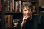 Neil Gaiman in front of a full bookshelf