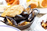 Cast iron bowl of mussels with sliced bread on top
