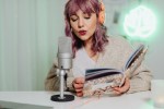 Woman speaking into a microphone while reading a book