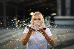 Woman blowing confetti off a book.