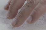 Close-up of a hand using a Braille document