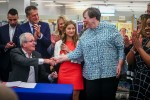 Martha Hickson, a recently retired media specialist who fought censorship at North Hunterdon High School in Annandale, New Jersey, shakes hands with New Jersey Gov. Phil Murphy (seated) after he signed into law last winter a measure to limit book bans and protect librarians from liability in the state. Photo: Dana DiFilippo/New Jersey Monitor