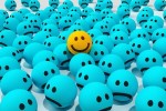 Yellow ball with a smiley emoji in a group of blue balls with frowning faces