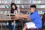 Two students working at a library table