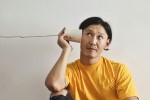 Man holding a tin can phone to his ear