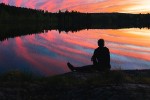Man contemplating by the water at sunset