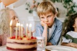 Unhappy-looking boy alone with a birthday cake