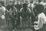 Nashville Children's Theatre photo depicting a group of children and one adults sit in chairs and on the floor, facing the camera in what appears to be an indoor gathering or event, reimagining a storytelling.