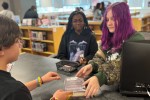 Two students checking out books in a school library