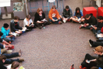 Students sitting on the floor in a circle, each reading.