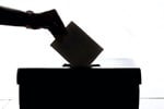 Silhouette of a person dropping a ballot into a box