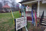 The "sunbrella," a bare-spoked umbrella with ribbons and bells hanging from its spokes, standing over the Storytelling Resource Center sign in front of its building.