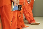 People in orange prison uniforms holding books