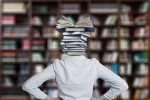 Woman in a library with a stack of books for her head
