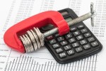 Coins in a vise with an accountant's calculator