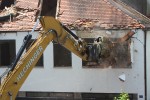 Excavator demolishing the wall of a building